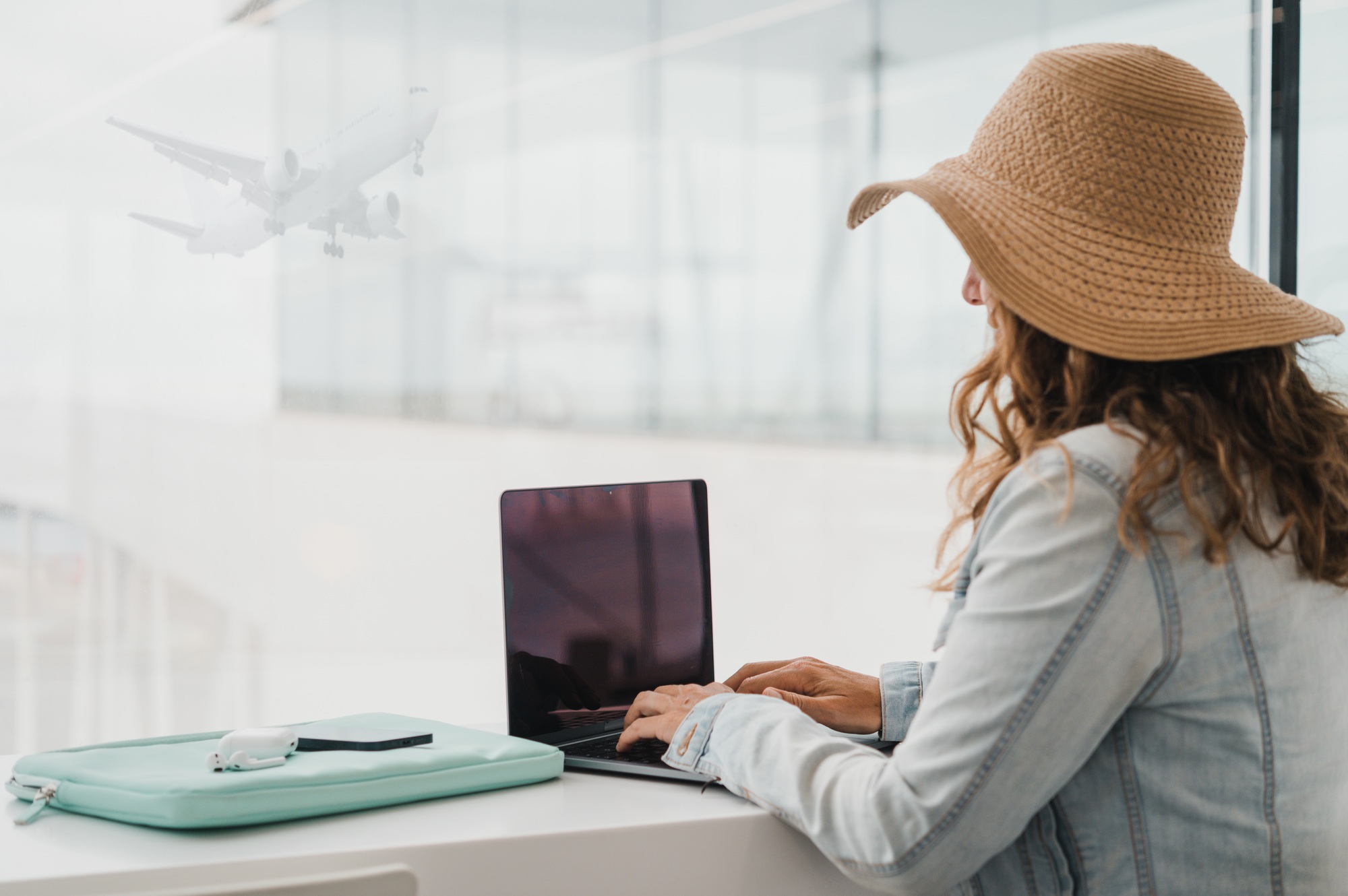 Woman using laptop at table near window in airport window